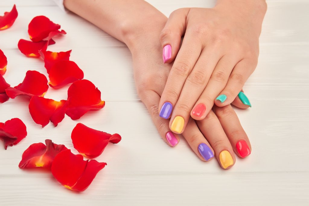Female hands with short multicolored nails